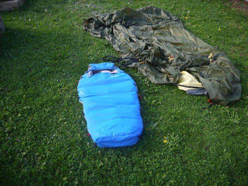 Sac de couchage enfant Helsport Mini Bright blue devant une tente en cours de montage